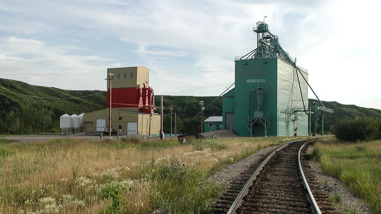 Prairie highway and grain elevators under a wide Alberta sky